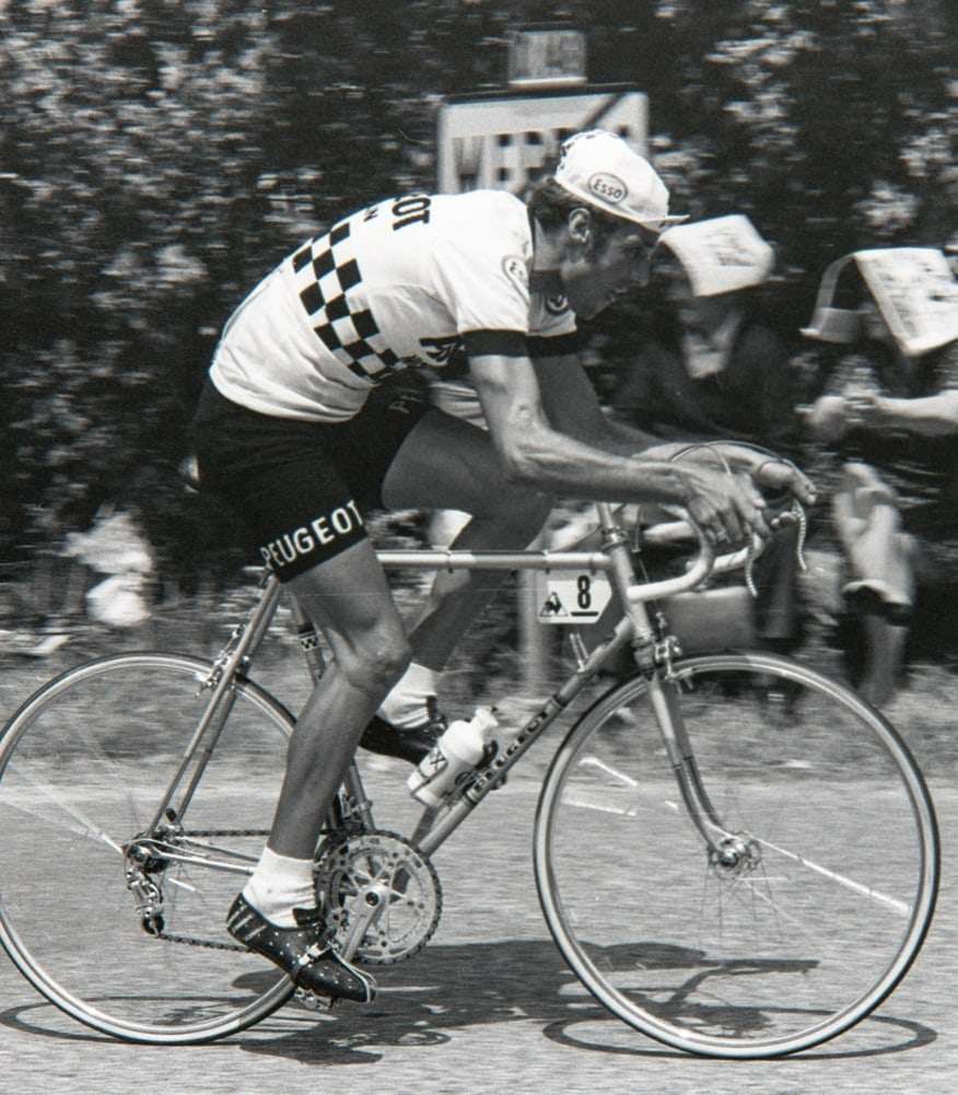 Régis Ovion en maillot Peugeot, penché sur son vélo, un bidon à la main