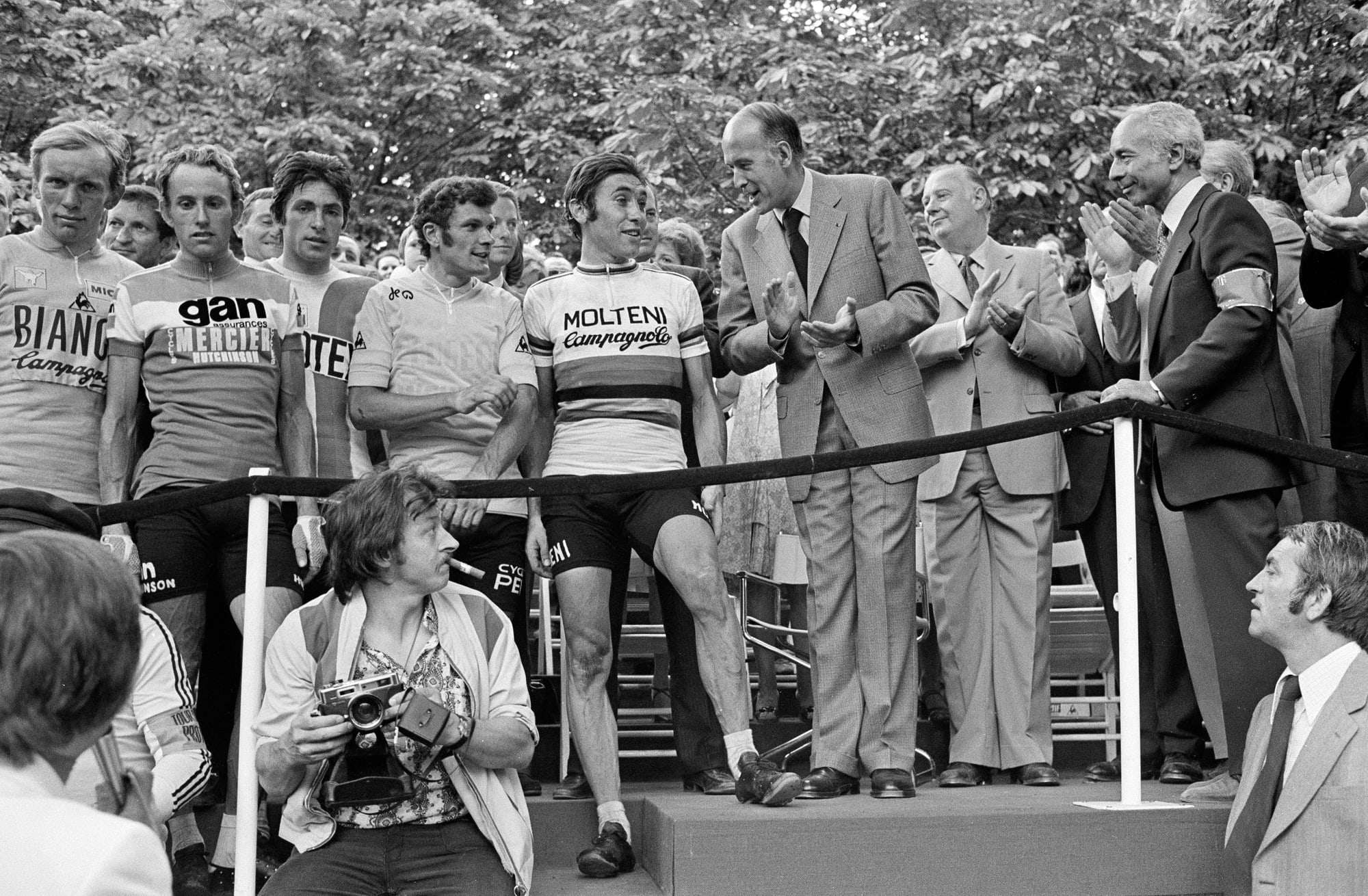 Podium de l'arrivée du Tour de France 1975 sur les Champs-Élysées, coureurs et officiels derrière un ruban